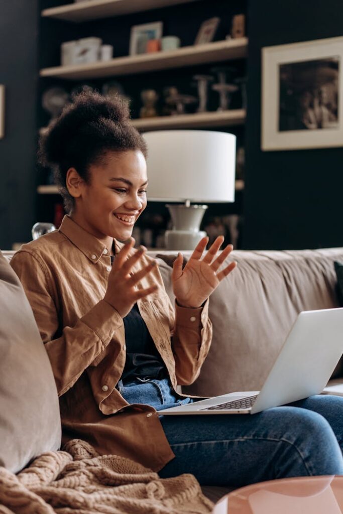 Happy woman enjoying remote work from home on laptop with cozy setup.
