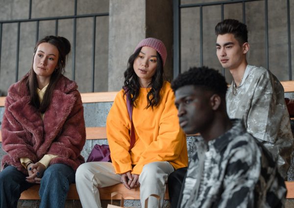 A diverse group of young adults sitting together, showcasing modern fashion and friendship.